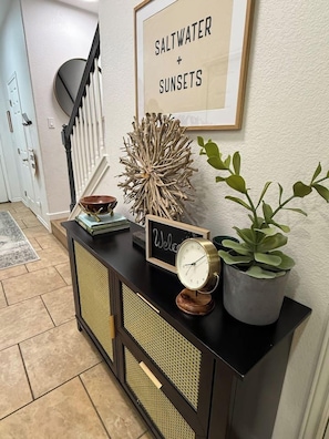 A black console table with a clock, a framed sign, decorative items, and a potted plant. - Private Boat Dock + Beach Access | Canal-Front (Corpus Christi)
