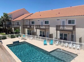 A swimming pool with a tiled deck, surrounded by white chairs and a white fence. - Private Boat Dock + Beach Access | Canal-Front (Corpus Christi)