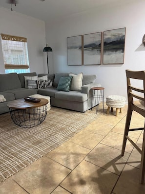 A living room with a sofa, a coffee table, a floor lamp, and a chair. - Private Boat Dock + Beach Access | Canal-Front (Corpus Christi)