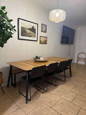 A dining area with a wooden table, black chairs, a hanging light fixture, and framed artwork on the wall. - Private Boat Dock + Beach Access | Canal-Front (Corpus Christi)