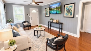 A living room with a sofa, armchairs, a coffee table, and a television mounted on the wall. - Portifino-Cozy on Charles (Montgomery)