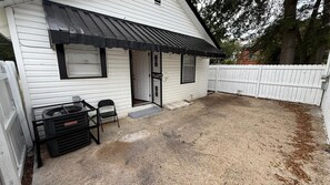 A white building with a black awning, a gravel driveway, and a white fence. - Portifino-Cozy on Charles (Montgomery)