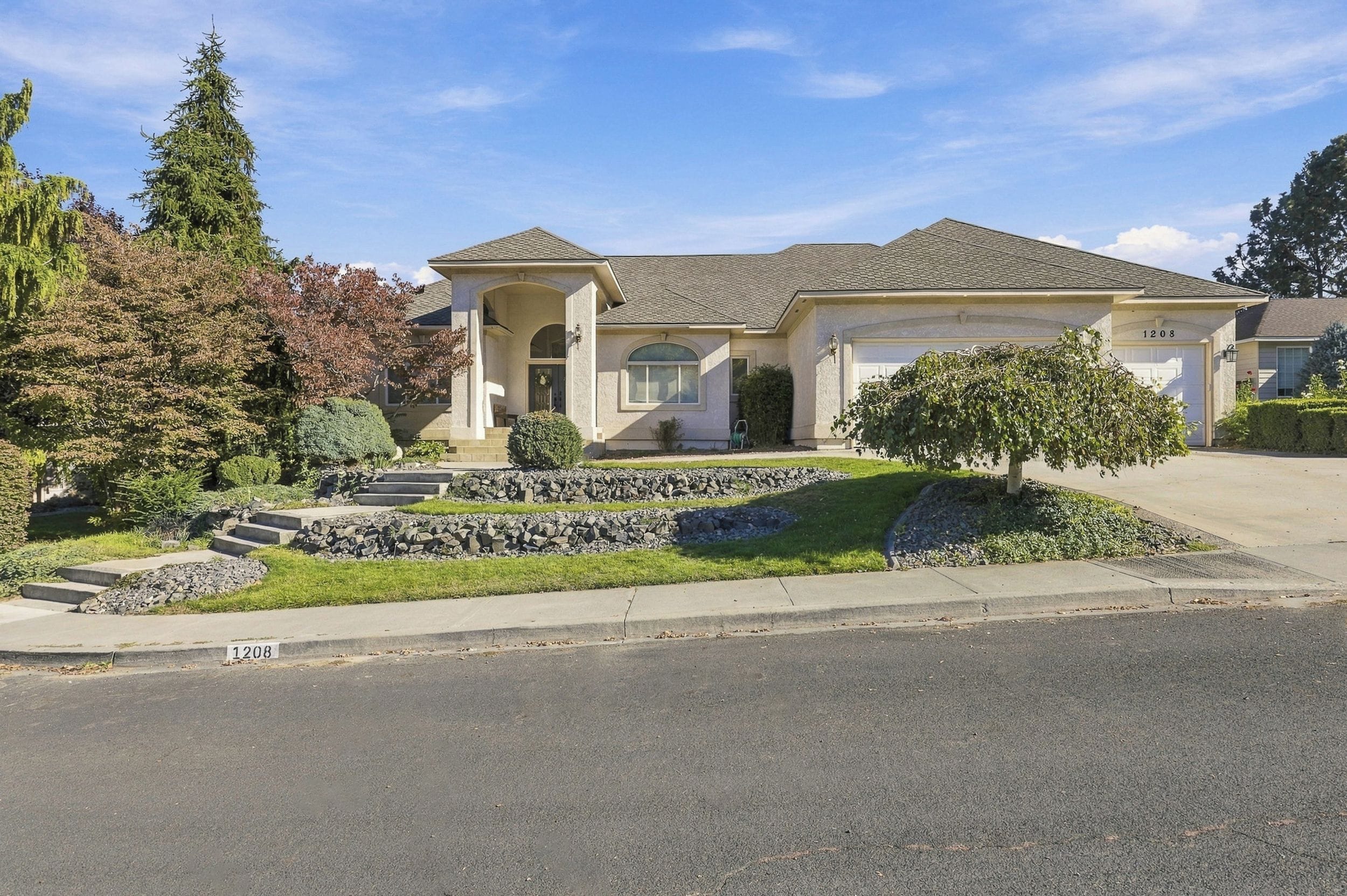 A two-story house with a stone retaining wall, a front porch, and a garage.
