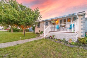 Ein Haus mit Veranda, Baum und Sonnenuntergangshimmel.