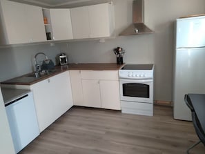 A kitchen with white cabinets, a wooden countertop, a built-in oven, and a dishwasher. - StaySmart Glitregata – 2-bedroom apartment with balcony in Kongsberg (Kongsberg)