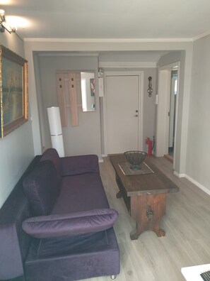 A living room with a purple sofa, a wooden coffee table, and a door leading to another room. - StaySmart Glitregata – 2-bedroom apartment with balcony in Kongsberg (Kongsberg)