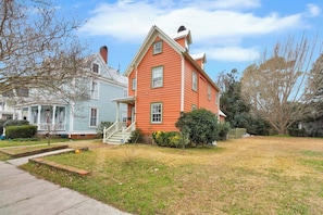 A two-story house with a front porch and a well-maintained lawn. - Downtown New Bern 3-Bed Home - Yard, Pet-Friendly! (New Bern)