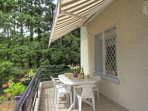 A balcony with a table and chairs, surrounded by greenery and a view of trees. - Cosy gîte with garden, pets allowed (Commelle-Vernay)