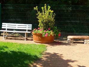 A bench, a planter with flowers, and a fence in a park. - Cosy gîte with garden, pets allowed (Commelle-Vernay)