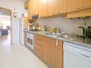 Eine moderne Küche mit Holzschränken, einer Edelstahlspüle und einem eingebauten Geschirrspüler.