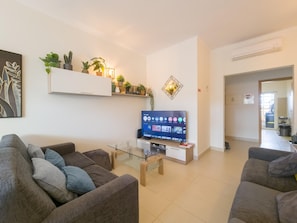 Ein Wohnzimmer mit einem Flachbildfernseher, zwei Sofas, einem Couchtisch und einem Bücherregal.
