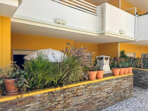 A balcony with a variety of potted plants, a white umbrella, and a small water feature. - Apartment with balcony pool access - 4 guests (Tavira)