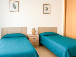 A bedroom with two beds, a nightstand, and two framed botanical prints on the wall. - Apartment with balcony pool access - 4 guests (Tavira)