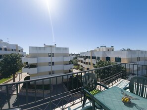 A balcony with a table and chairs, overlooking a residential area with multi-story buildings. - Cozy apartment, Eastern Algarve - 4 guests (Tavira)