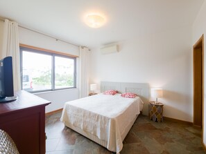 Ein Hotelzimmer mit Bett, Nachttischen, Schreibtisch und Fernseher.