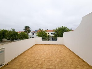 An outdoor terrace with a tiled floor, surrounded by white walls and a view of buildings with red roofs. - Villa with air conditioning in Altura - 6 guests (Altura)