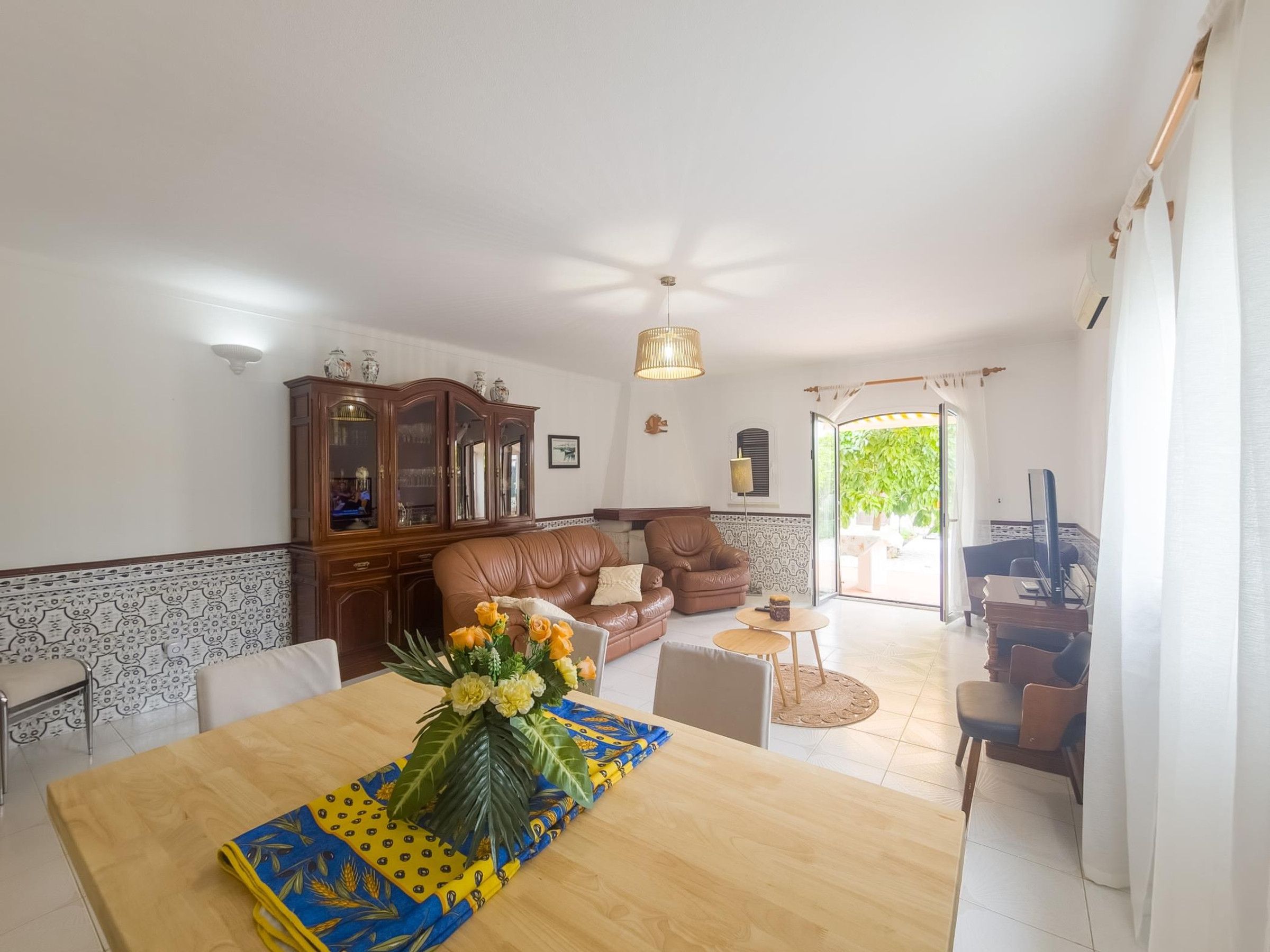 A dining area with a wooden table, chairs, and a vase of flowers.
