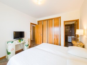 Ein Hotelzimmer mit einem Bett, einem Fernseher auf einem Schreibtisch, einem Kleiderschrank und einem durch eine offene Tür einsehbaren Badezimmer.