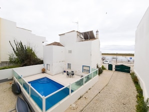 A residential building with a rooftop pool, a patio with seating, and a view of the sea. - Eclectic apartment in the heart of Cabanas - 3 guests (Tavira)
