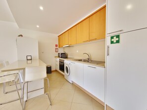 A compact kitchen with a washing machine, a microwave, and a sink. - Modern apartment near Ria Formosa (Tavira)