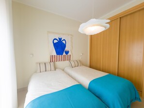 A room with two beds, a wooden wardrobe, a wall-mounted artwork, and a hanging light fixture. - Apartment with rooftop terrace - 4 guests (Tavira)