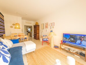 A living room with a television, a dining area, and a kitchen in the background. - Apartment with rooftop terrace - 4 guests (Tavira)