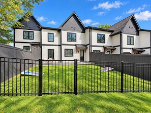A two-story residential building with a fenced backyard, a well-maintained lawn, and a patio area. - Luxury 4 Bed 4.5 Bath Townhome-3010 (Homewood)