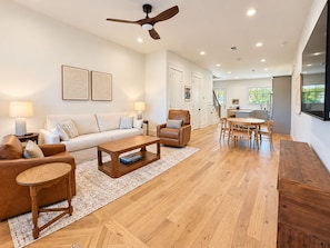 A modern living room with a sofa, coffee table, and chairs, a dining area with a table and chairs, and a kitchen in the background. - Luxury 4 Bed 4.5 Bath Townhome-3010 (Homewood)