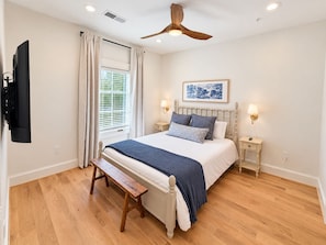 A bedroom with a bed, a bench, a ceiling fan, a window with blinds, and a wall-mounted TV. - Luxury 4 Bed 4.5 Bath Townhome-3010 (Homewood)