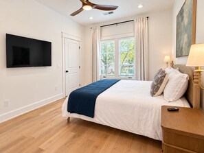 A bedroom with a bed, a TV mounted on the wall, a ceiling fan, and a window with curtains. - Luxury 4 Bed 4.5 Bath Townhome-3010 (Homewood)