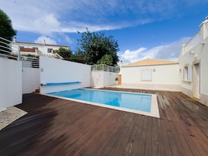A swimming pool with a wooden deck, surrounded by white walls and a tiled roof. - Villa with private pool and AC - Tavira (Tavira)