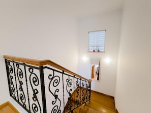 Eine Treppe mit einem hölzernen Geländer und schwarzen Metallspindeln.