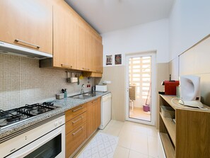 A kitchen with wooden cabinets, a gas stove, a sink, and a coffee machine. - Apartment with AC - 4 guests Near beach (Tavira)