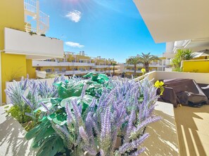 A balcony with potted lavender plants, a yellow wall, and a view of a residential area. - Apartment with AC - 4 guests Near beach (Tavira)