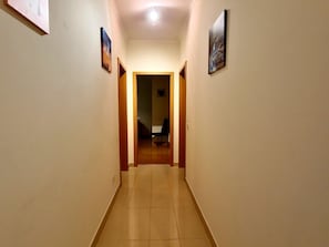 A hallway with a tiled floor, wooden doors, and framed pictures on the walls. - Bright apartment in Tavira - 6 guests (Tavira)