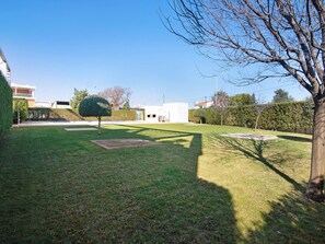 A well-maintained lawn with a trimmed bush and a tree. There are buildings in the background. - Central apartment with AC - 4 guests (Tavira)