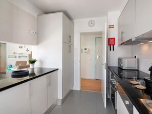 A modern kitchen with white cabinets, a black countertop, and stainless steel appliances. - Central apartment with AC - 4 guests (Tavira)