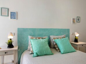 A bedroom with a bed, two nightstands, a lamp, a potted plant, and wall art. - Central apartment with AC - 4 guests (Tavira)