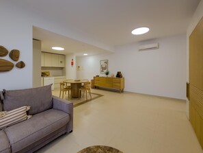 Un salon moderne avec un canapé, une table à manger et une cuisine en arrière-plan.