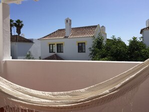 Ein Balkon mit einer weißen Wand und einer beigen Hängematte.
