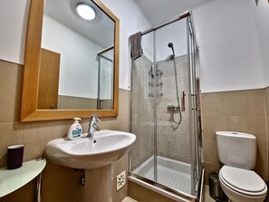A bathroom with a sink, mirror, shower, and toilet. - Apartment with pool - 4 guests (Tavira)