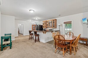 A spacious kitchen with wooden cabinets, a central island, and a dining area with wooden chairs. - Spacious 6-bedroom house in beautiful Fredericksburg with AC (Fredericksburg)