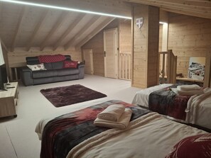 A cozy room with a sofa, two beds, a red rug, and wooden walls. - Cozy chalet for 6 in Châtel with WiFi and parking (Châtel)