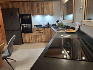 A modern kitchen with wooden cabinets, a black refrigerator, and a stainless steel stove. - Cozy chalet for 6 in Châtel with WiFi and parking (Châtel)
