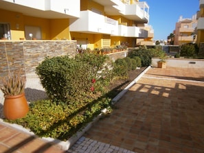 A residential building with balconies, a paved courtyard, and potted plants. - Apartment with pool and garden - 4 guests (Tavira)