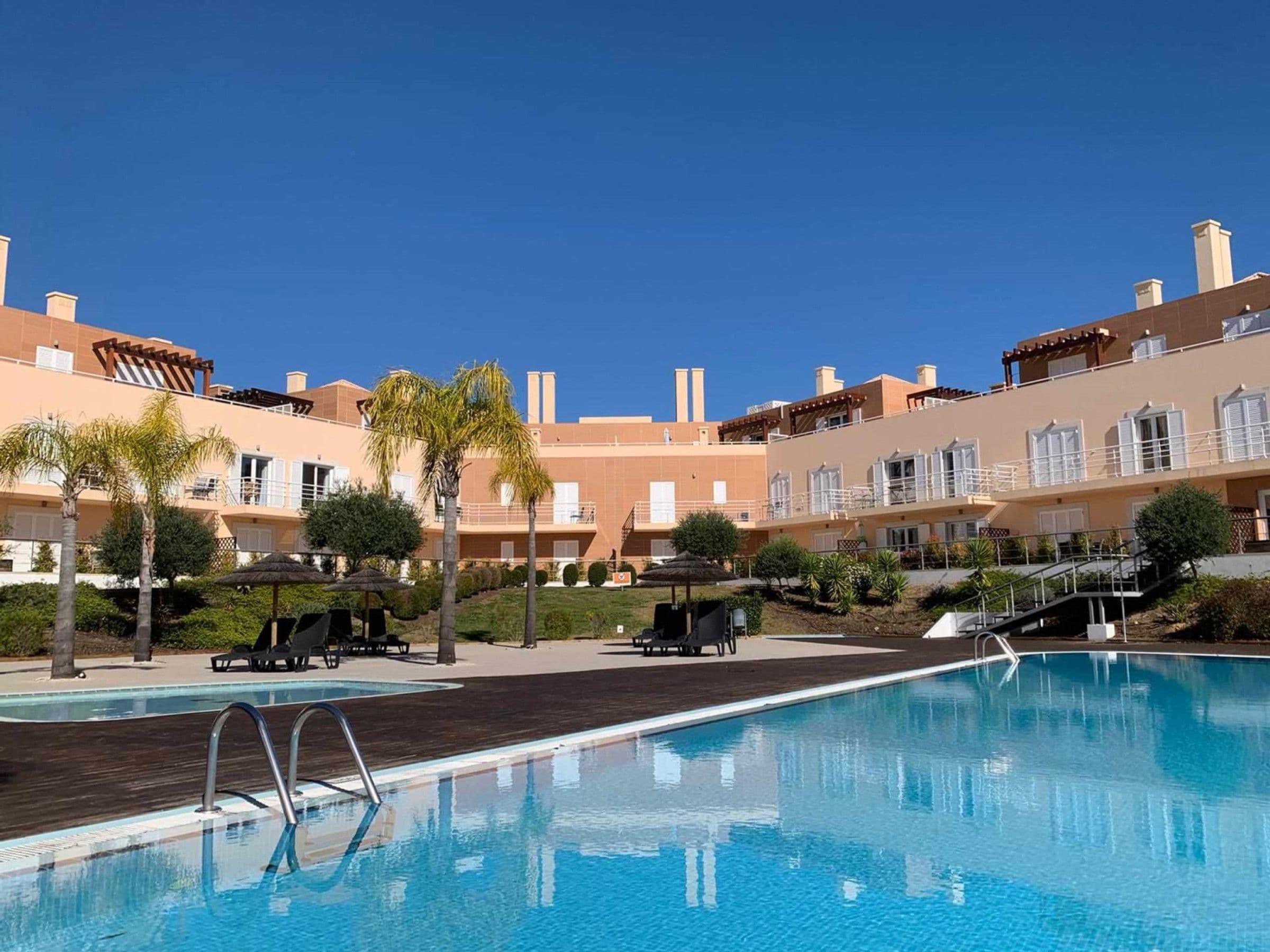 Una piscina con sillas de descanso y cielo despejado.