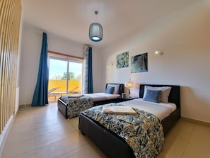 A hotel room with two beds, a balcony with a yellow wall, and a ceiling light fixture. - Spacious apartment with air conditioning - 6 guests (Tavira)