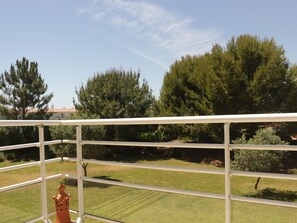 A balcony with a white railing overlooking a well-maintained lawn and trees. - Apartment with AC - 2+2 guests (Tavira)