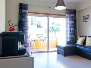 A modern living room with a sofa, a coffee table, and a dining area with chairs. - 2-bedroom apartment near Tavira (Tavira)