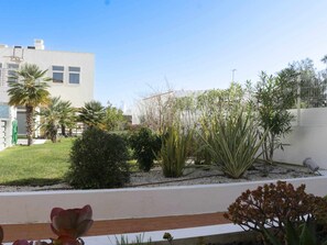 A landscaped garden with various plants and a white building in the background. - Stylish apartment with air conditioning - 4 guests (Tavira)